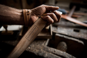 Mann hält robusten Ledergürtel in der Hand – strapazierfähiger Gürtel für Alltag und Arbeit.