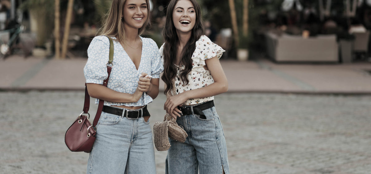 Zwei junge Frauen tragen Jeans mit lässigen Ledergürteln mit Vollschließe aus echtem Leder – stilvoll kombiniert für einen modernen Casual-Look
